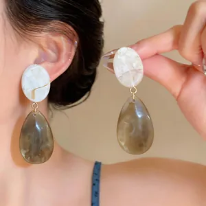 Detail of vintage resin drop earrings with marble oval stud and amber teardrop pendant