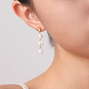 Primo piano di eleganti orecchini pendenti con perle d'acqua dolce e zirconi su modella