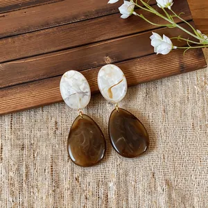 Close-up of vintage resin drop earrings with elegant brown and white marbled texture