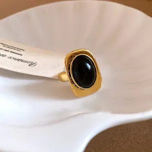 Close-up view of a vintage gold-toned open ring featuring a large oval black gemstone on a white shell