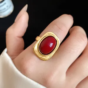 Macro close-up of a vintage gold ring featuring a large red oval stone on a finger