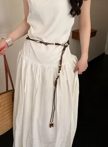 Detailansicht einer böhmischen braunen geflochtenen Tailenkette mit Perlen auf weißem Kleid