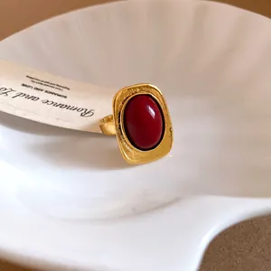 Close-up of vintage gold-toned open ring with a large oval red stone in a shell dish.