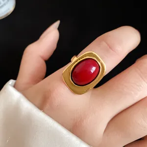 Detail of a vintage gold-toned rectangular ring with a bold red oval stone worn on a finger