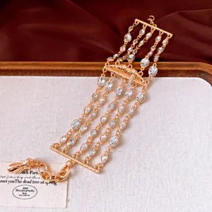 Dettaglio di un bracciale dorato multistrato con ciondolo a forma di labbra e strass brillanti