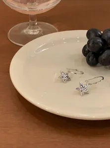 Detailed view of silver Y2K star drop earrings with sparkling zirconia on a white plate