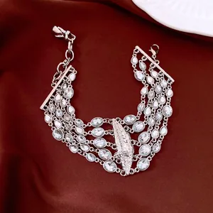Dettaglio di un bracciale multistrato argentato con cristalli ovali su seta rossa elegante.