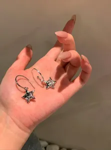 Close-up of elegant Y2K silver star earrings with sparkling crystals held in a hand