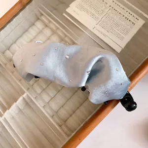 Primo piano di un fermaglio a banana in raso azzurro a pieghe con piccoli strass.