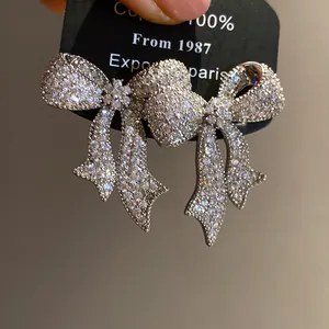 Detalle de pendientes de lazo con aguja de plata y piedras de circonio brillantes