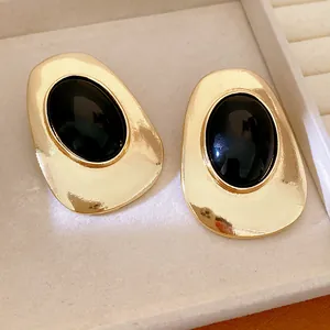 Close-up of elegant gold stud earrings featuring large black oval stones in a jewelry tray.