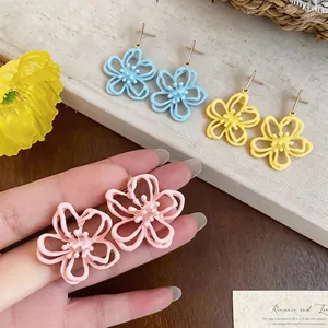 Nahaufnahme von eleganten hohlen Blumenohrsteckern mit buntem Tropföl-Emaille-Finish