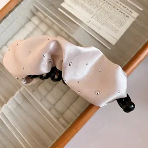 Primo piano di un'elegante clip a banana in raso plissettato con strass