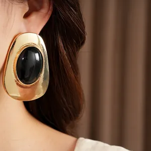 Detailed close-up view of vintage gold stud earring with black oval stone on model