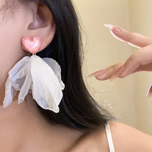 Detailed view of pink heart and white fabric petal tassel earring on model's ear