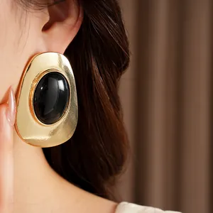 Close-up detail showing the vintage gold textured earring with a large black oval stone