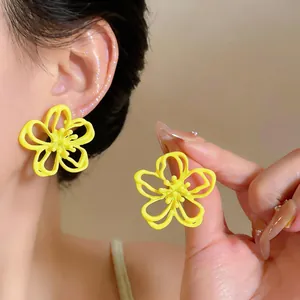 Detaillierte Makroaufnahme von leuchtend gelben hohlen Blumenohrsteckern an Ohr und Hand