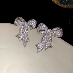 Vista detallada de pendientes de lazo de plata con circonitas brillantes incrustadas.