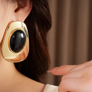 Close-up of elegant gold-toned vintage earrings with a black oval center stone