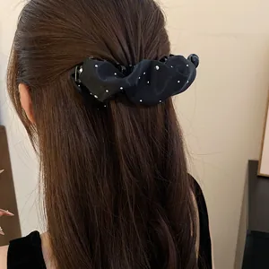 Primo piano di un fermaglio a banana francese in tessuto plissettato nero sui capelli