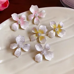 Elegant frosted flower stud earrings with shimmering texture on a decorative tray