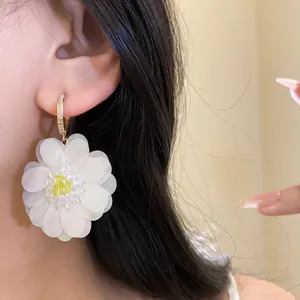 Detail view showing the delicate texture of a large white fabric flower earring on ear