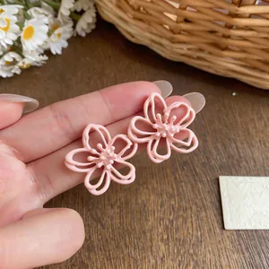 Detailaufnahme der mattrosa ausgehöhlten Blumen-Ohrstecker mit zarten Blütenblättern