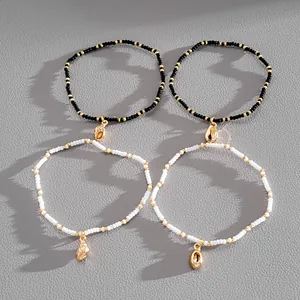 Detail shot of four boho bead bracelets with gold shell charms on grey background