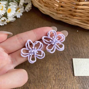Detaillierte Nahaufnahme hellvioletter hohler Blumenohrstecker mit Tropföl-Finish