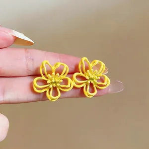 Detailansicht von leuchtend gelben hohlgeformten Blumenohrsteckern mit Silbernadel.