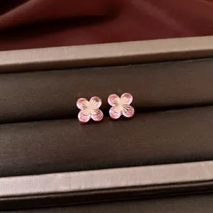 Close-up of pink zircon flower earrings in a velvet jewelry box with golden details.