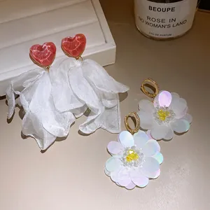 Close-up detail of white fabric flower and red heart fringe earrings on an elegant display