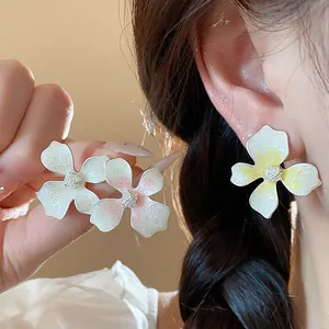 Close-up of elegant flower earrings with shimmering drip oil finish in pink and yellow