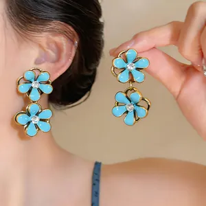Detailed macro view of elegant blue flower earrings with rhinestone center and silver needles.