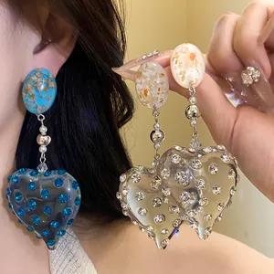 Detail of vintage resin heart earrings with sparkling blue and clear rhinestones.