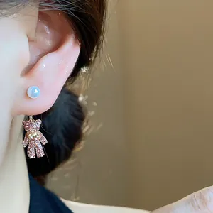 Detailansicht eines rosa diamantbesetzten Bärenohrrings mit einem weißen Perlenstecker