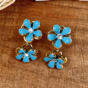 Close-up detail of blue enamel flower drop earrings with a sparkling crystal center