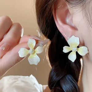 Elegant white and yellow flower stud earrings with silver needles and textured enamel finish.
