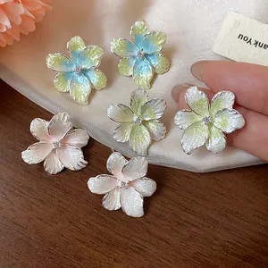 Gros plan de boucles d'oreilles fleurs en émail coloré avec un détail central en zircon
