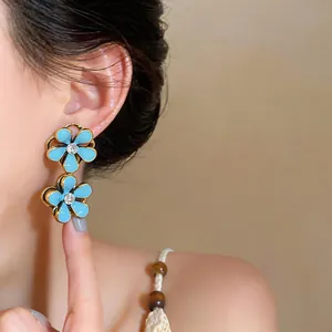 Detailed view of blue floral drop earrings with enamel finish and crystal accents