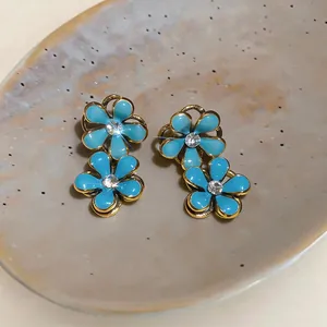 Detailed macro view of light blue enamel flower earrings with central rhinestones