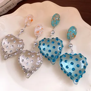 Detailed macro view of vintage heart resin earrings with sparkling inlaid rhinestones.