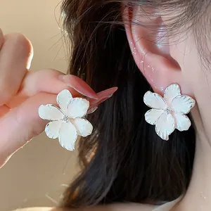 Vue détaillée de clous d'oreilles fleur en émail blanc avec détail en zircon étincelant