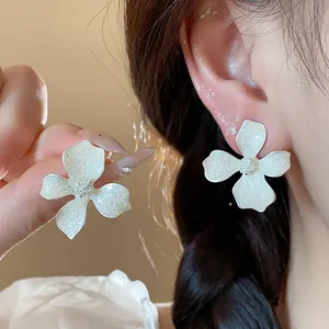 Close-up view of elegant white textured flower stud earrings worn on ear for women fashion