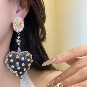 Detailed close-up of a vintage resin heart earring featuring rhinestones and pearl accents