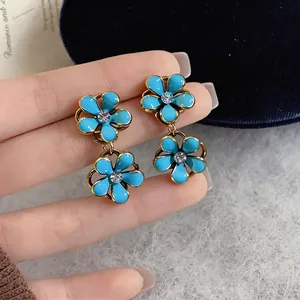 Detailed macro shot of blue enamel flower drop earrings with central sparkling rhinestones