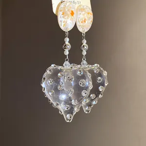 Macro detail view of vintage resin heart earrings studded with sparkling rhinestones