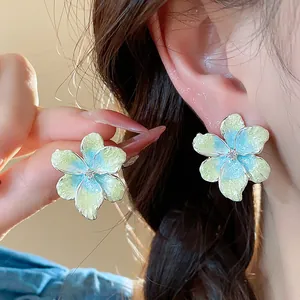 Gros plan de boucles d'oreilles fleurs dopamine avec émail bleu et jaune brillant