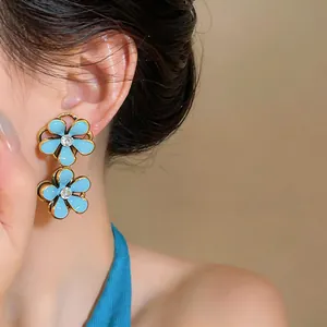 Close-up view of elegant blue enamel flower earrings with sparkling crystal centers