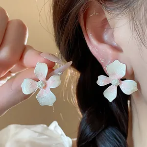 Close-up detail of elegant white and pink floral enamel stud earrings with glitter finish